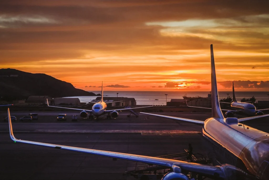 A stunning airport sunset with luxury aircraft lined up, symbolizing seamless travel and smooth transitions with LuxeRides' premium transfer services.