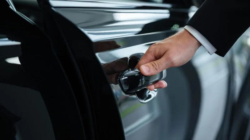 A professional chauffeur opening a luxury vehicle door – LuxeRides' exclusive travel agent and hotel partnership service in the UK.